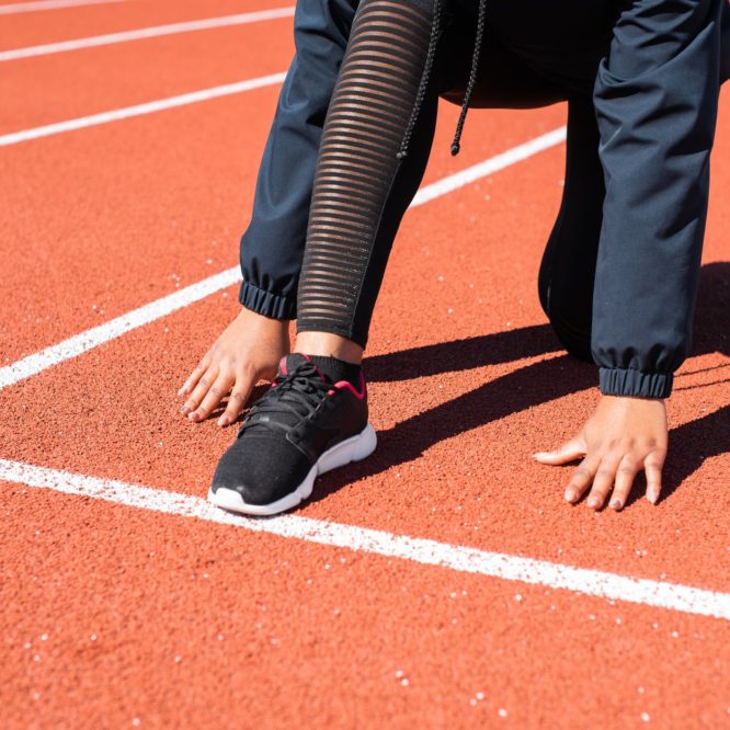 person in black pants and black leather shoes standing on track field